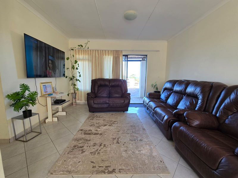 A functional living room featuring tiled flooring and a sliding glass door providing access to the outdoor area.