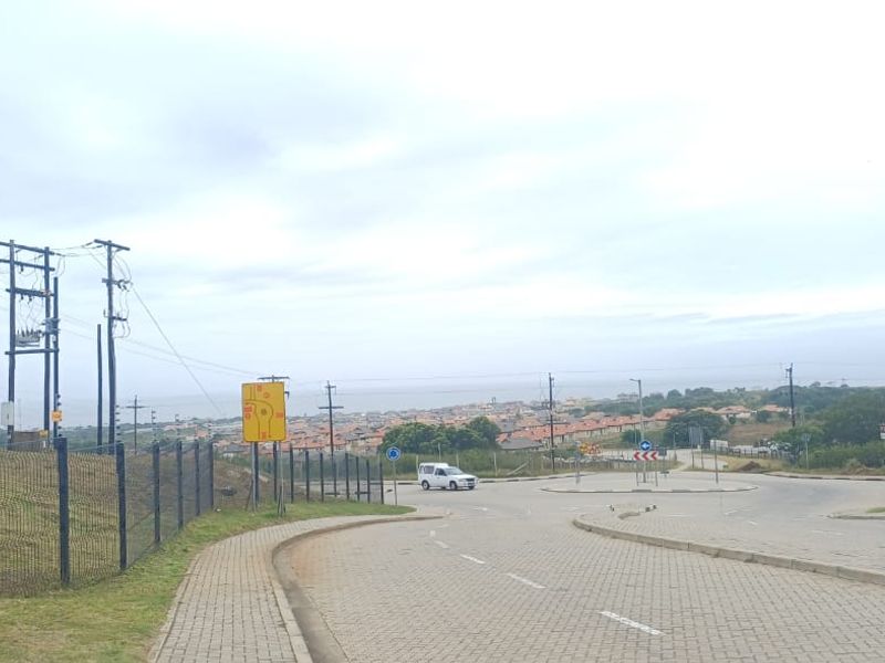 A street view showing the approach to the neighborhood with paved roads, sidewalks, and utility infrastructure.