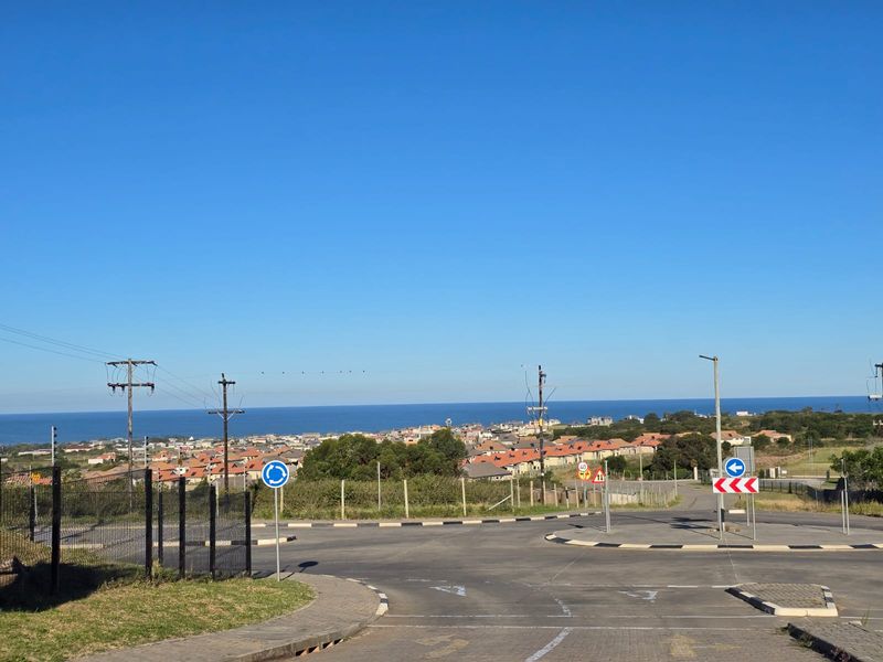 A street view showing the local road infrastructure, traffic signage, and surrounding neighbourhood with a distant ocean view.