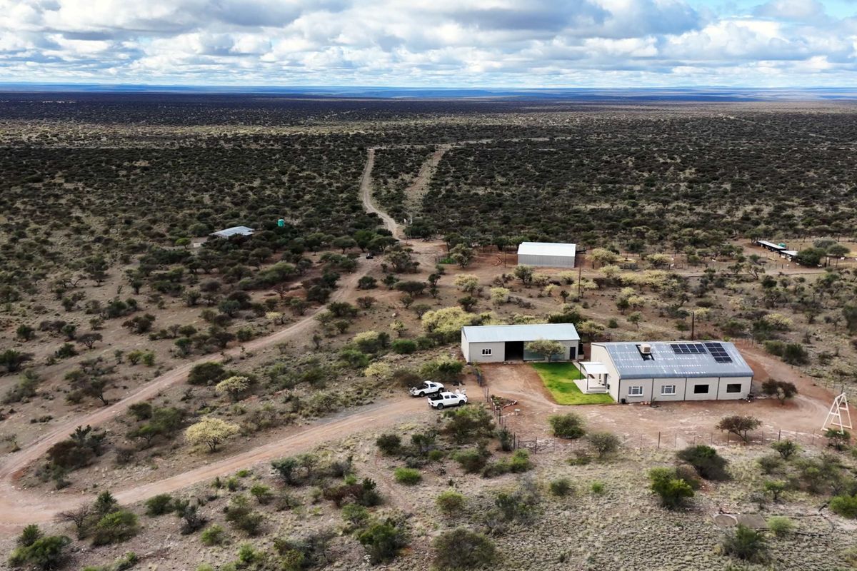 Aerial view of a rural farm property featuring a main residence with solar panels, multiple outbuildings, and extensive surrounding land.