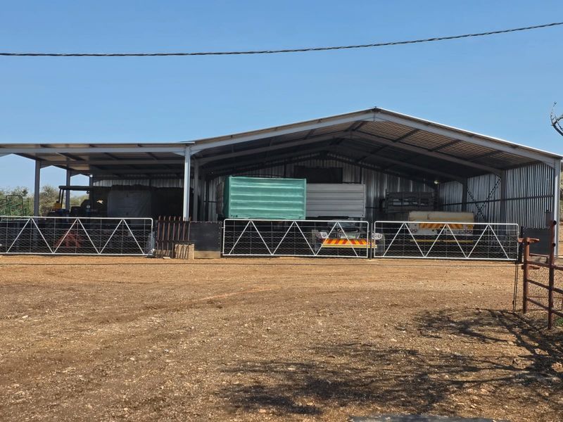 A large, open-sided steel-framed farm shed with corrugated metal roofing and cladding, suitable for machinery storage or agricultural utility purposes.