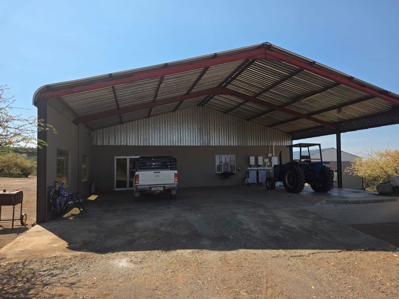 Large open-sided farm shed or garage featuring a durable steel frame, corrugated metal roofing, and concrete flooring, suitable for vehicle storage or workshop use.