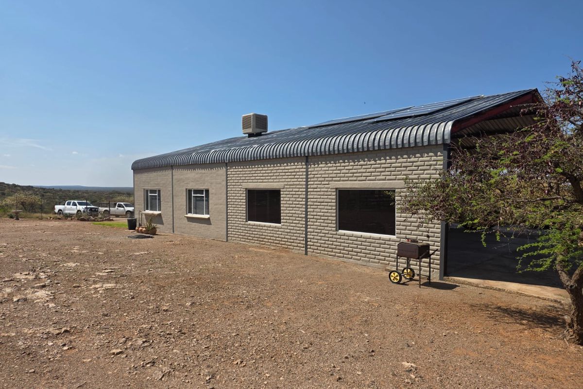 Rear view of a farm building featuring a corrugated metal roof with integrated solar panels, brick masonry walls, and tinted windows.
