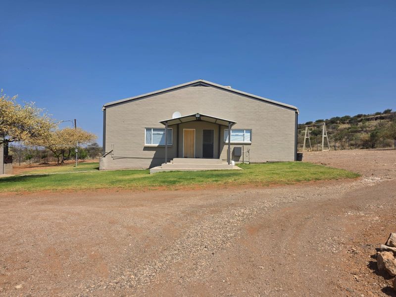 Front elevation of a single-story farm dwelling featuring a covered entrance porch, concrete steps, and a gravel driveway approach.