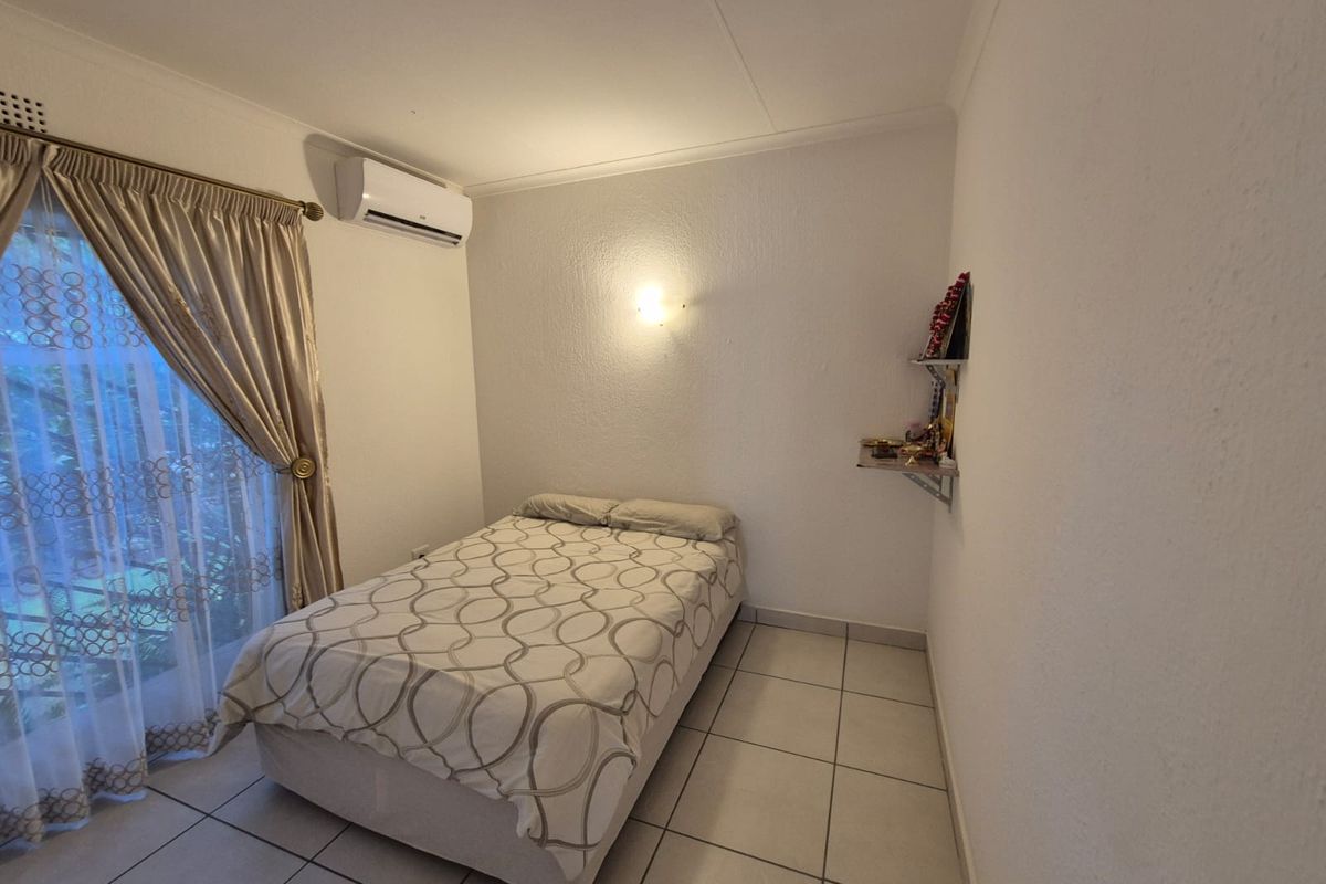 A bedroom featuring tiled flooring, a wall-mounted air conditioning unit, and a sliding door with curtains leading to an outdoor area.