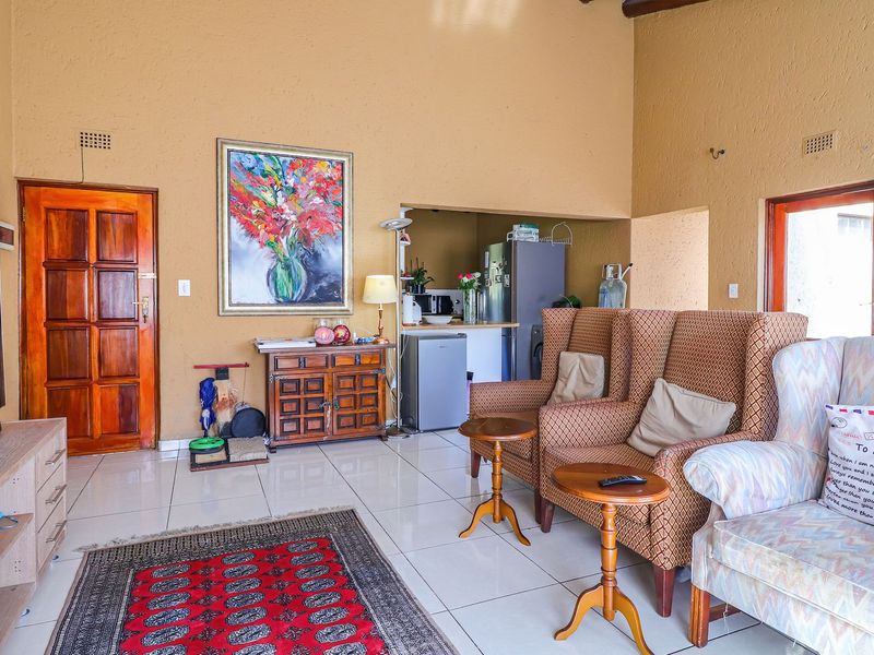 Open-plan living area featuring high vaulted ceilings, tiled flooring, and a convenient pass-through window connecting to the kitchen space.