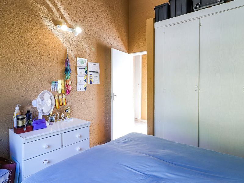 Bedroom featuring a built-in wardrobe and textured wall finish, offering a functional space with potential for cosmetic updates.