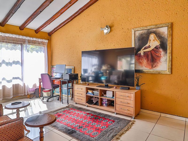 Living room featuring exposed timber ceiling beams, textured walls, and tiled flooring with access to an outdoor area via sliding glass doors.