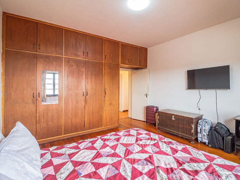 A bedroom featuring extensive floor-to-ceiling built-in wooden cabinetry and warm hardwood flooring.