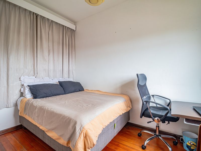 A functional bedroom featuring hardwood flooring and a large window with curtain track, offering a neutral space ready for personalization.