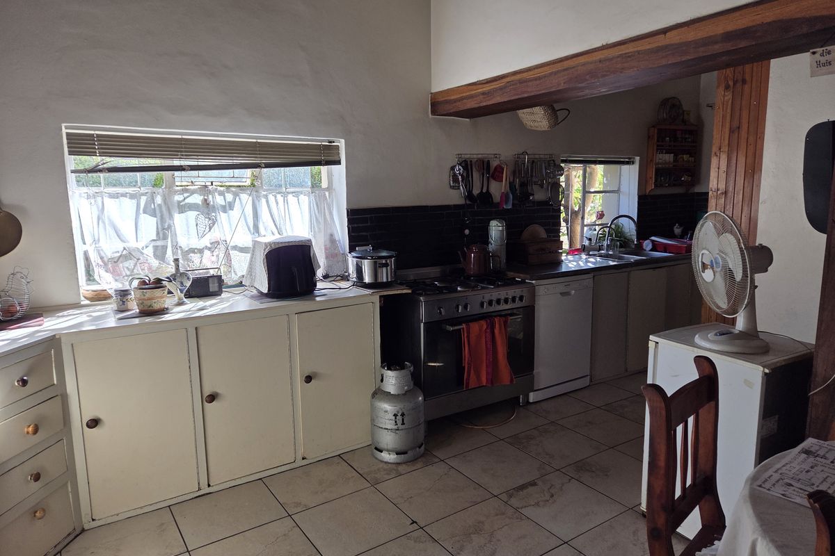 A rustic kitchen featuring tiled flooring, built-in cabinetry, a gas stove, and a stainless steel sink with a window view.
