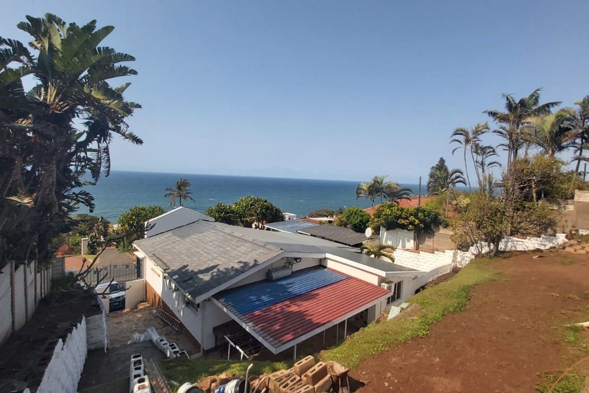 An elevated view of the property showing the roof structure, surrounding grounds, and a scenic ocean outlook.