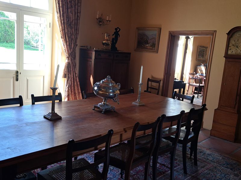 A traditional dining room featuring terracotta floor tiles and classic french doors leading to the exterior, creating a warm and inviting atmosphere.