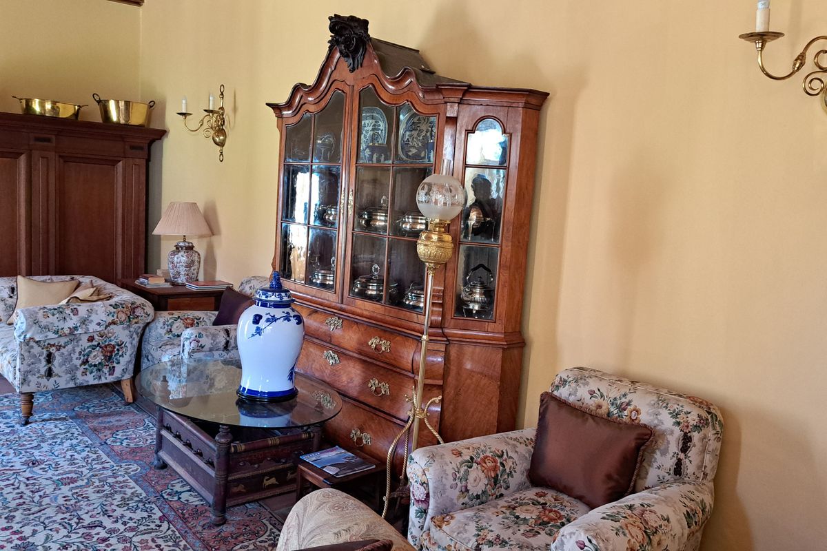 A traditional living room featuring warm-toned walls, classic wall sconces, and terracotta floor tiles, creating a cozy and historic atmosphere.