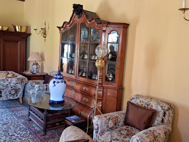 A traditional living room featuring warm-toned walls, classic wall sconces, and terracotta floor tiles, creating a cozy and historic atmosphere.