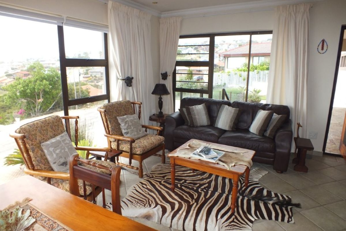 A bright living room featuring large windows with natural light, tiled flooring, and expansive views of the surrounding neighborhood.