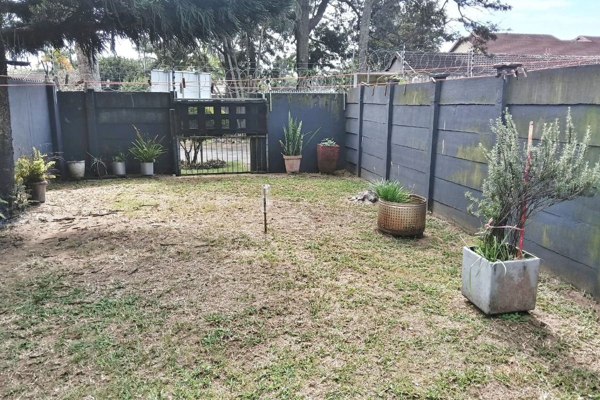 A private rear garden area enclosed by precast concrete walls with security razor wire and a metal access gate.