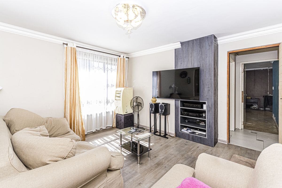 A comfortable living room featuring laminate flooring, crown molding, and a custom built-in media unit for television and entertainment storage.