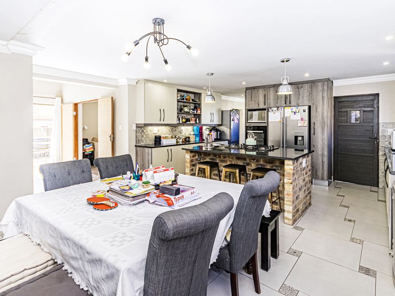 Spacious open-plan kitchen and dining area featuring a central brick-base island, modern cabinetry, granite countertops, and tiled flooring throughout.
