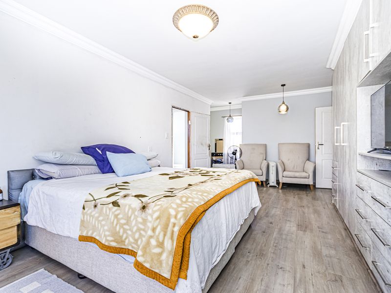 Spacious bedroom featuring light-toned laminate flooring, built-in cupboards, and decorative ceiling coving, offering a bright and functional living space.