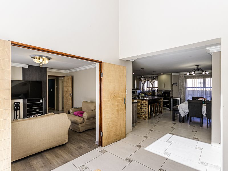 Spacious open-plan living area featuring a seamless transition between the lounge and kitchen, highlighted by tiled and laminate flooring and exposed brick accents.