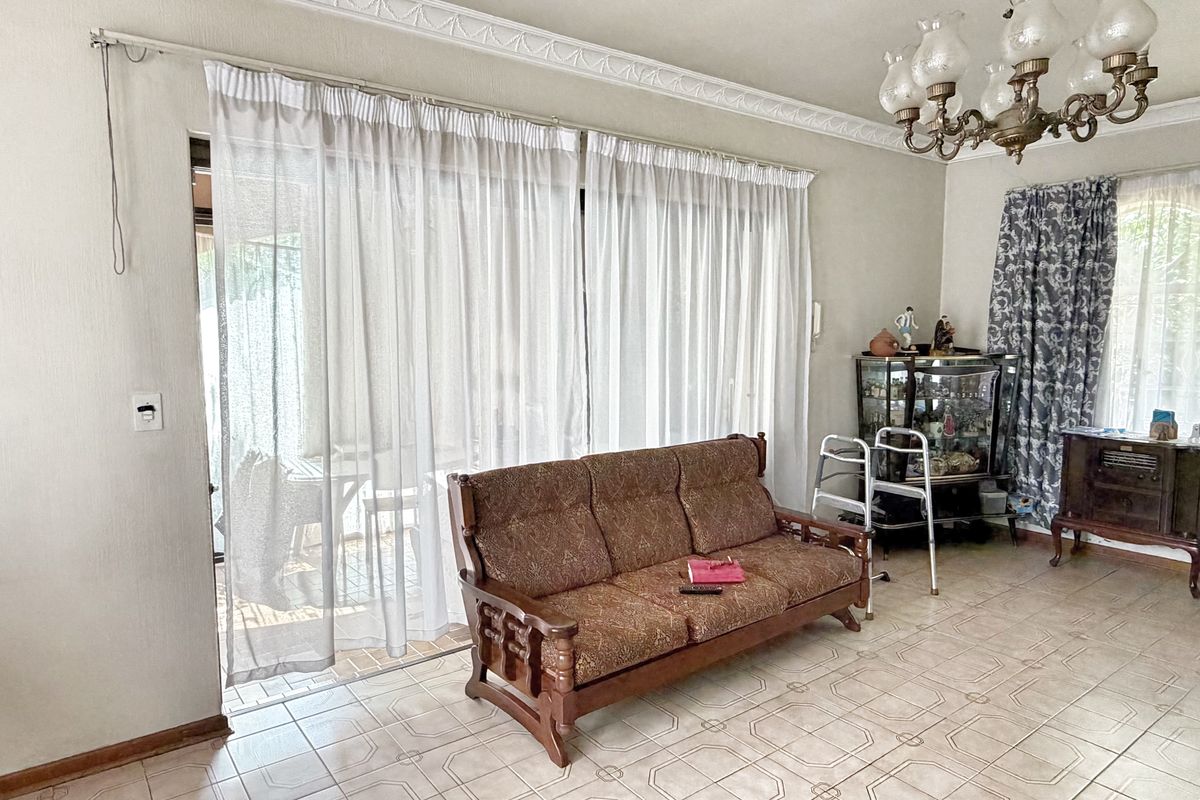A living room featuring ceramic floor tiles, decorative ceiling cornices, and a large sliding glass door providing access to the outdoor area.