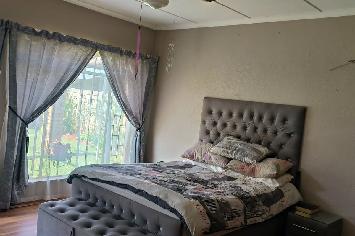 Spacious bedroom featuring laminate flooring, a ceiling fan, and a large sliding glass door providing access to the garden area.