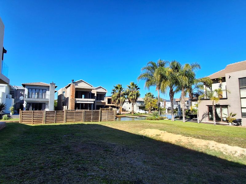 A view of the rear garden area featuring a lawn, timber fencing, and surrounding residential properties.