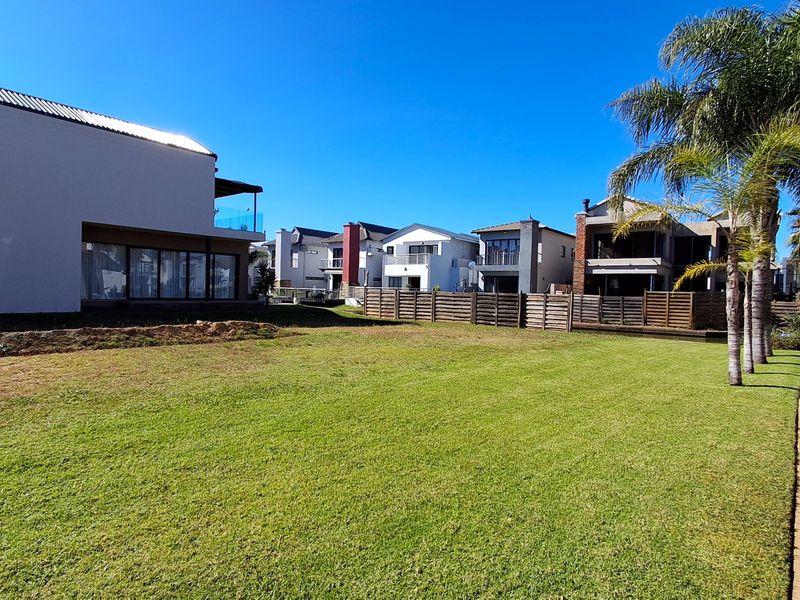 A well-maintained residential garden featuring a manicured lawn, paved walkway, and timber boundary fencing in a suburban estate setting.
