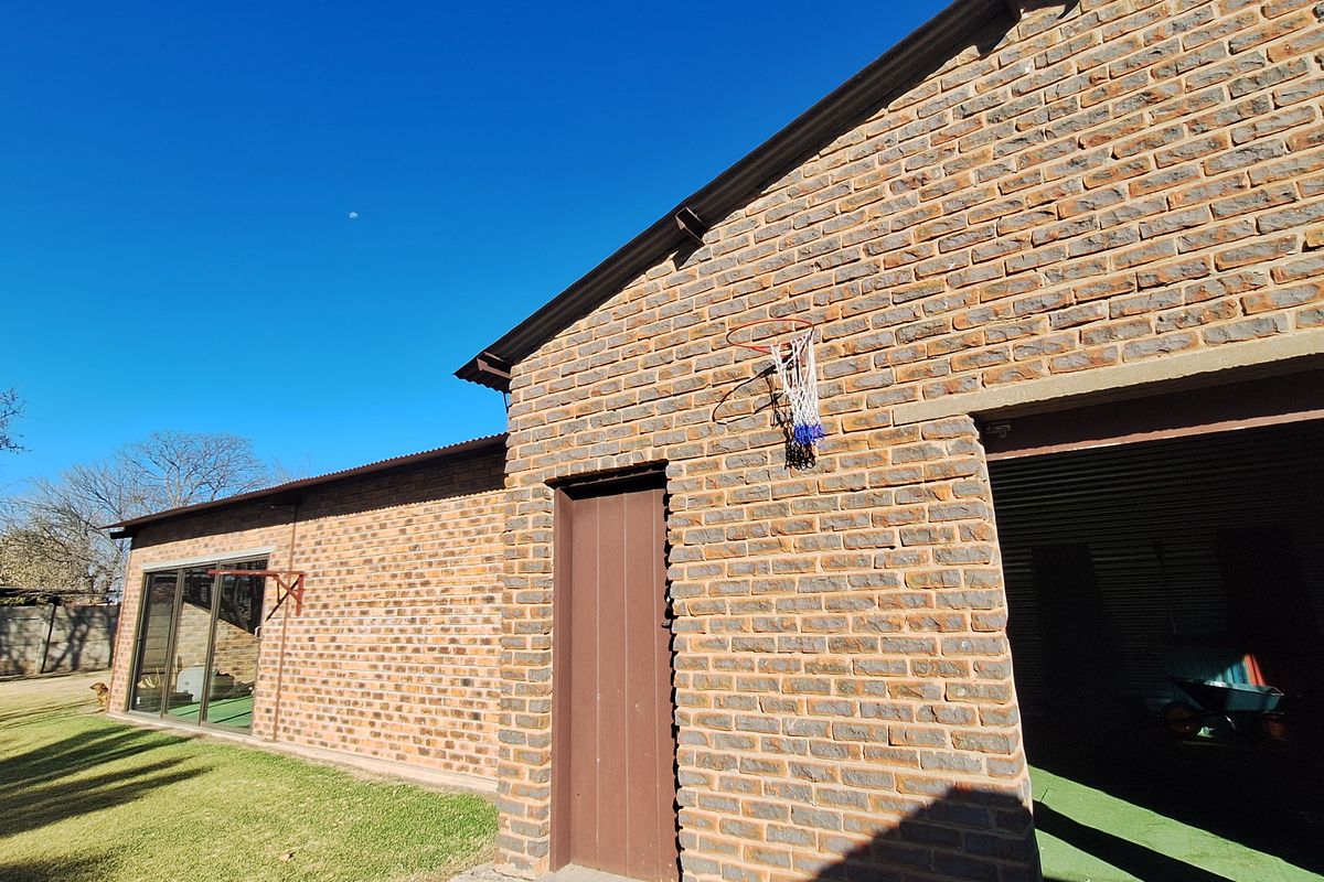 Rear view of a face brick house featuring a sliding glass door, a garage entrance, and a well-maintained lawn.