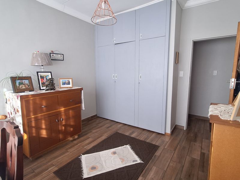 A well-maintained bedroom featuring built-in cupboards, laminate flooring, and decorative crown molding.