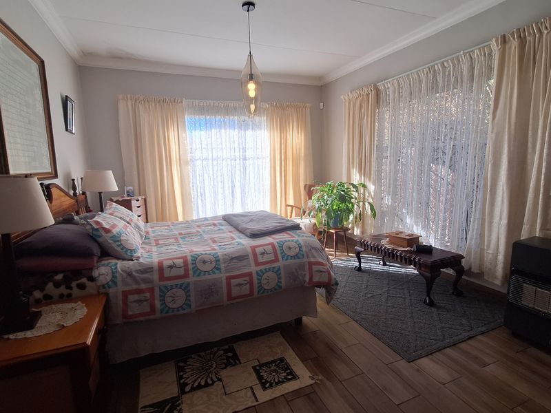 A well-lit bedroom featuring wood-look tile flooring, coved ceilings, and large windows that provide ample natural light.