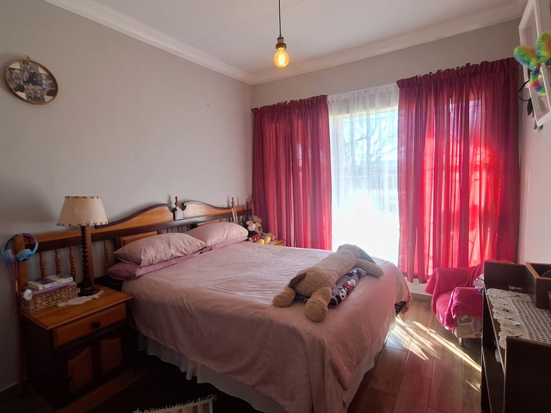 A cozy bedroom featuring wood-look tile flooring, cove cornicing, and a central pendant light fixture, offering a comfortable and functional living space.