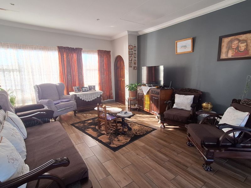 A spacious living room featuring wood-look tile flooring, a dark accent wall, and an arched wooden door, providing a warm and inviting atmosphere.