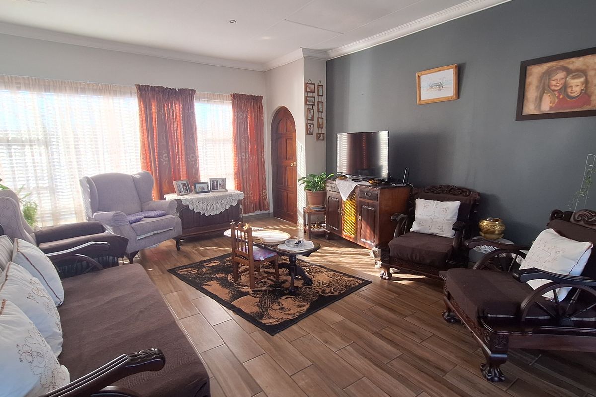 A spacious living room featuring wood-look tile flooring, a dark accent wall, and an arched wooden door, providing a warm and inviting atmosphere.