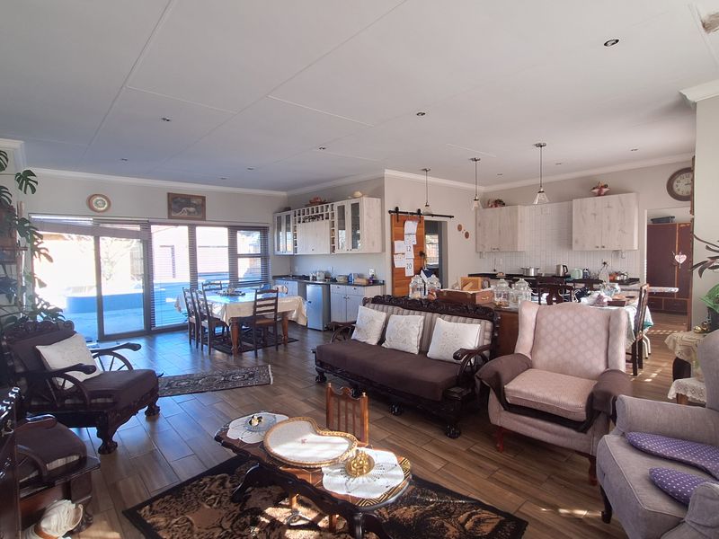 Spacious open-plan living and kitchen area featuring wood-look tiled flooring, recessed lighting, and direct access to the outdoor patio through sliding glass doors.