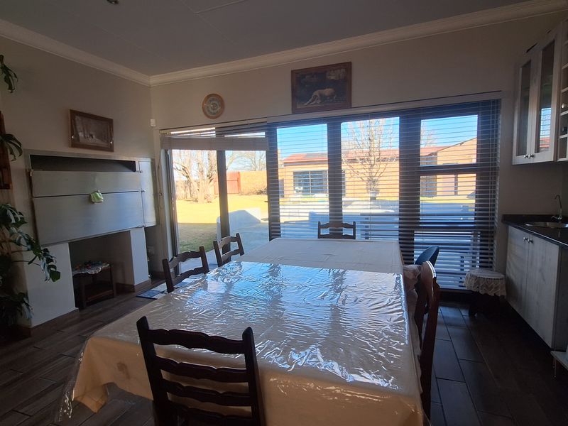Open plan dining area featuring a built-in braai, tiled flooring, and large sliding doors providing direct access to the rear garden.