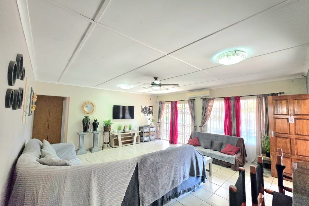 Spacious living room featuring tiled flooring, a ceiling fan, and split-system air conditioning, with direct access to the exterior through security gates.