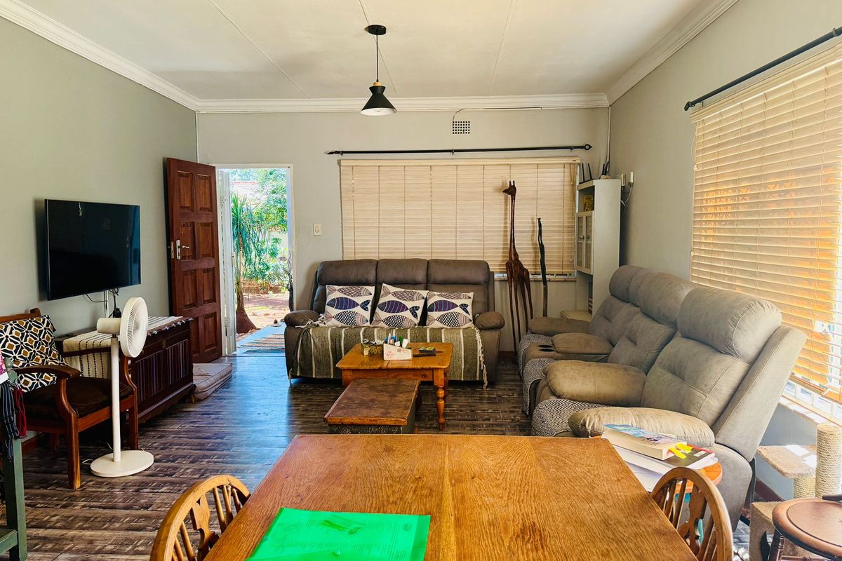 A comfortable living room featuring wood-look flooring, crown molding, and direct access to an outdoor area through a wooden door.