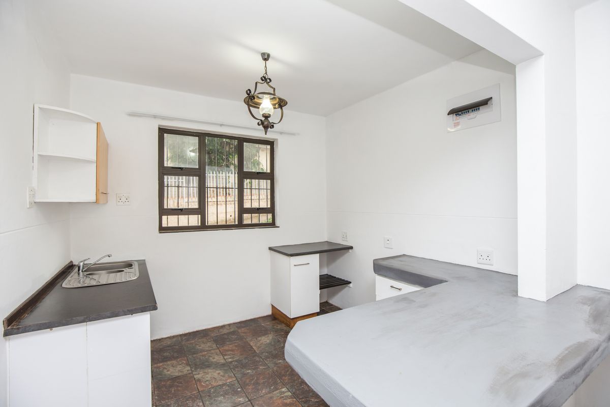 A functional kitchen area featuring built-in cabinetry, a stainless steel sink, and a breakfast bar counter with tiled flooring.