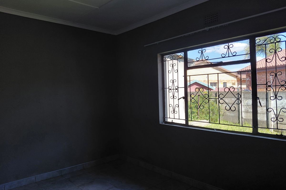 An empty bedroom featuring tiled flooring and security bars on the window, providing a blank canvas for potential interior design.