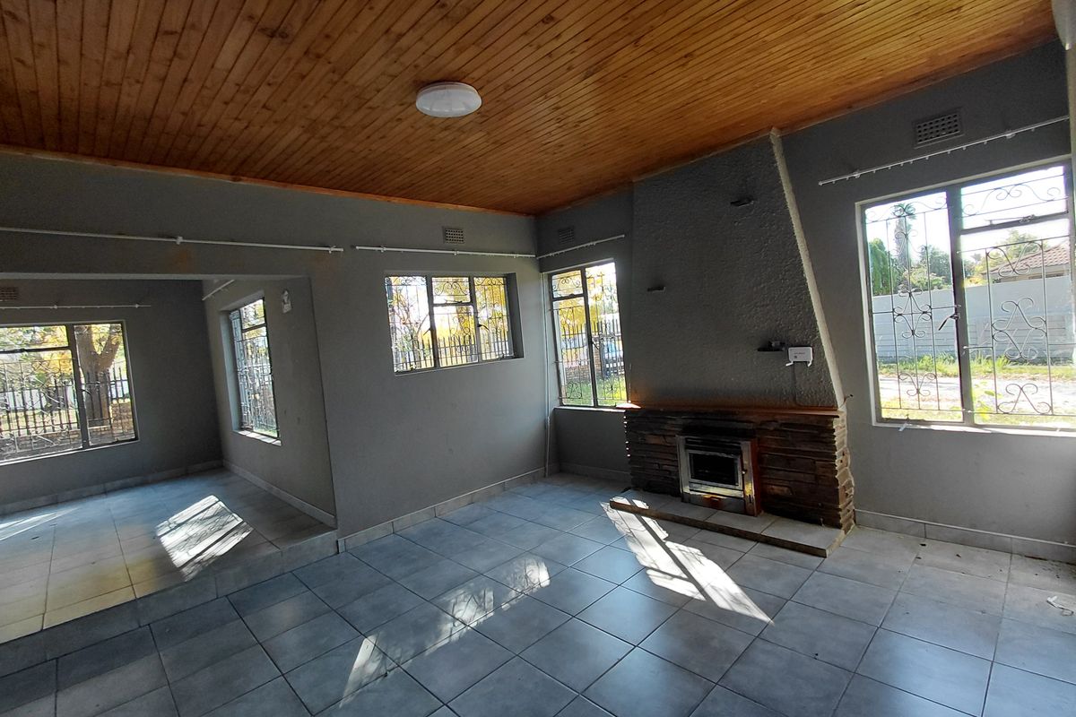 Spacious living area featuring a timber ceiling, tiled floors, and a built-in fireplace, offering a blank canvas for interior design.