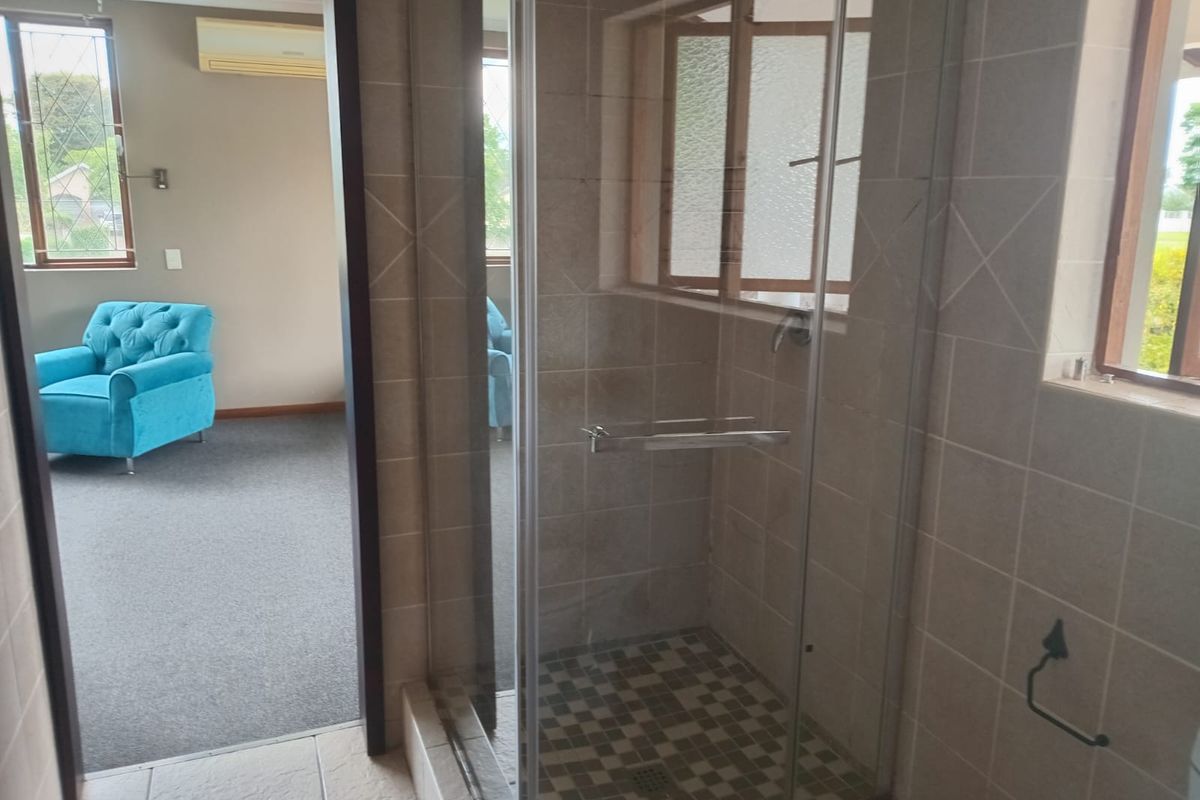A bathroom featuring a glass-enclosed shower with tiled walls and flooring, providing a functional space with direct access to an adjacent living area.