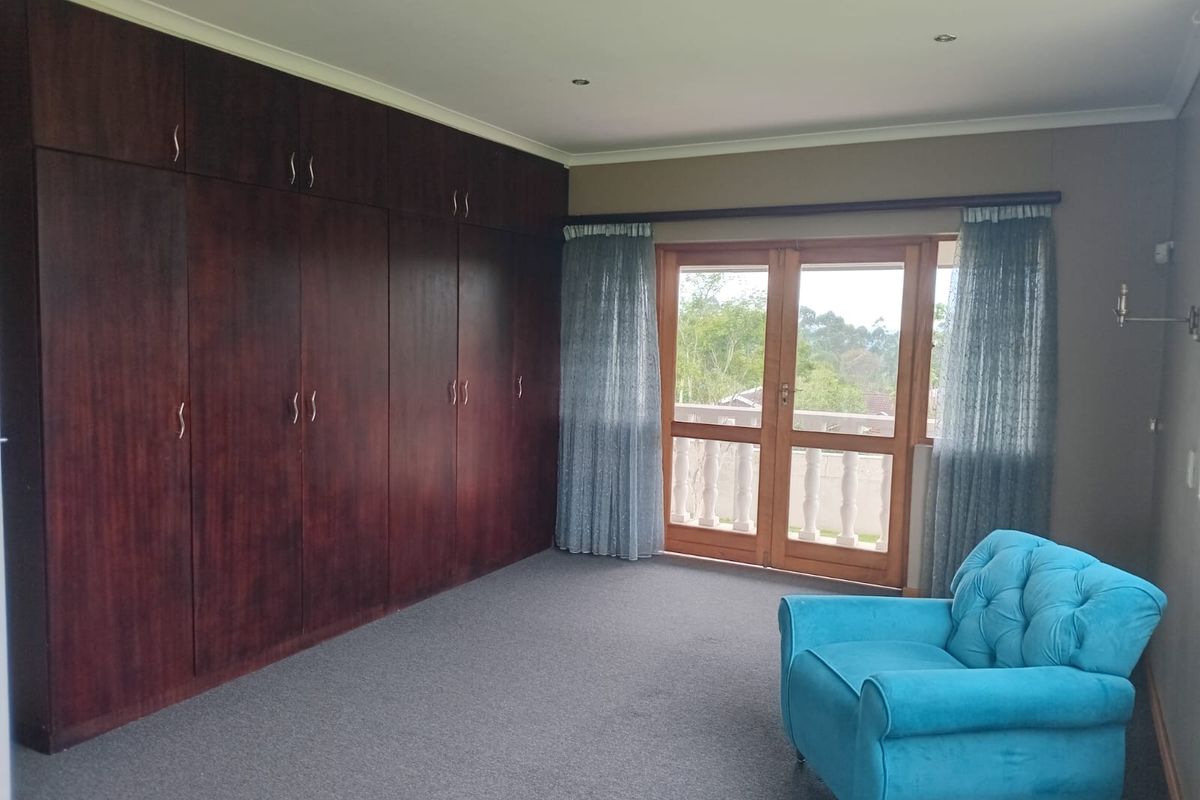 Spacious bedroom featuring extensive floor-to-ceiling built-in wooden cabinetry and double doors opening onto a private balcony with scenic views.