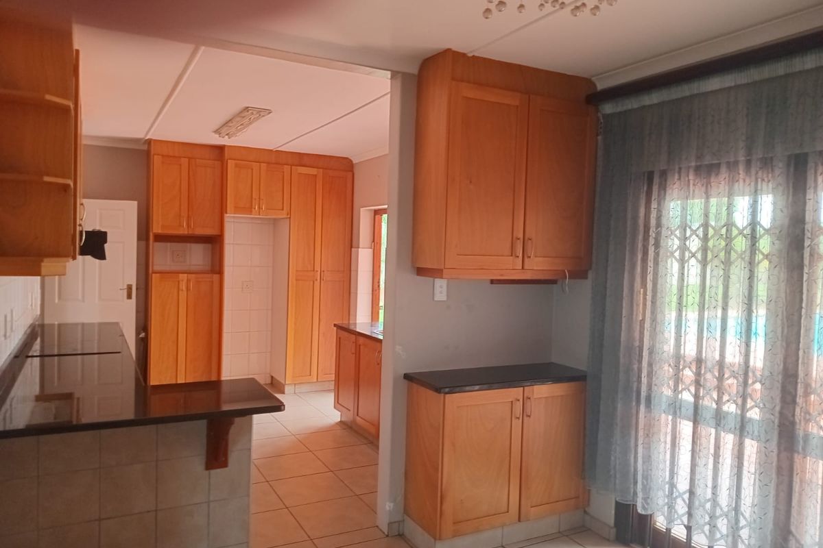 A functional kitchen featuring wooden cabinetry, dark countertops, and tiled flooring, with direct access to the outdoor area through a sliding glass door.