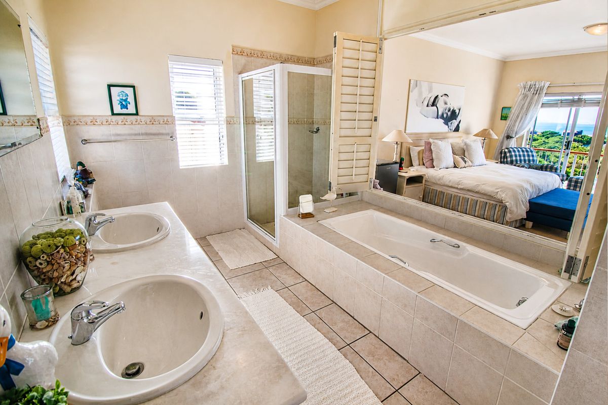 En-suite bathroom featuring a double vanity, glass-enclosed shower, and a built-in bathtub, with an open-plan connection to the adjacent bedroom.