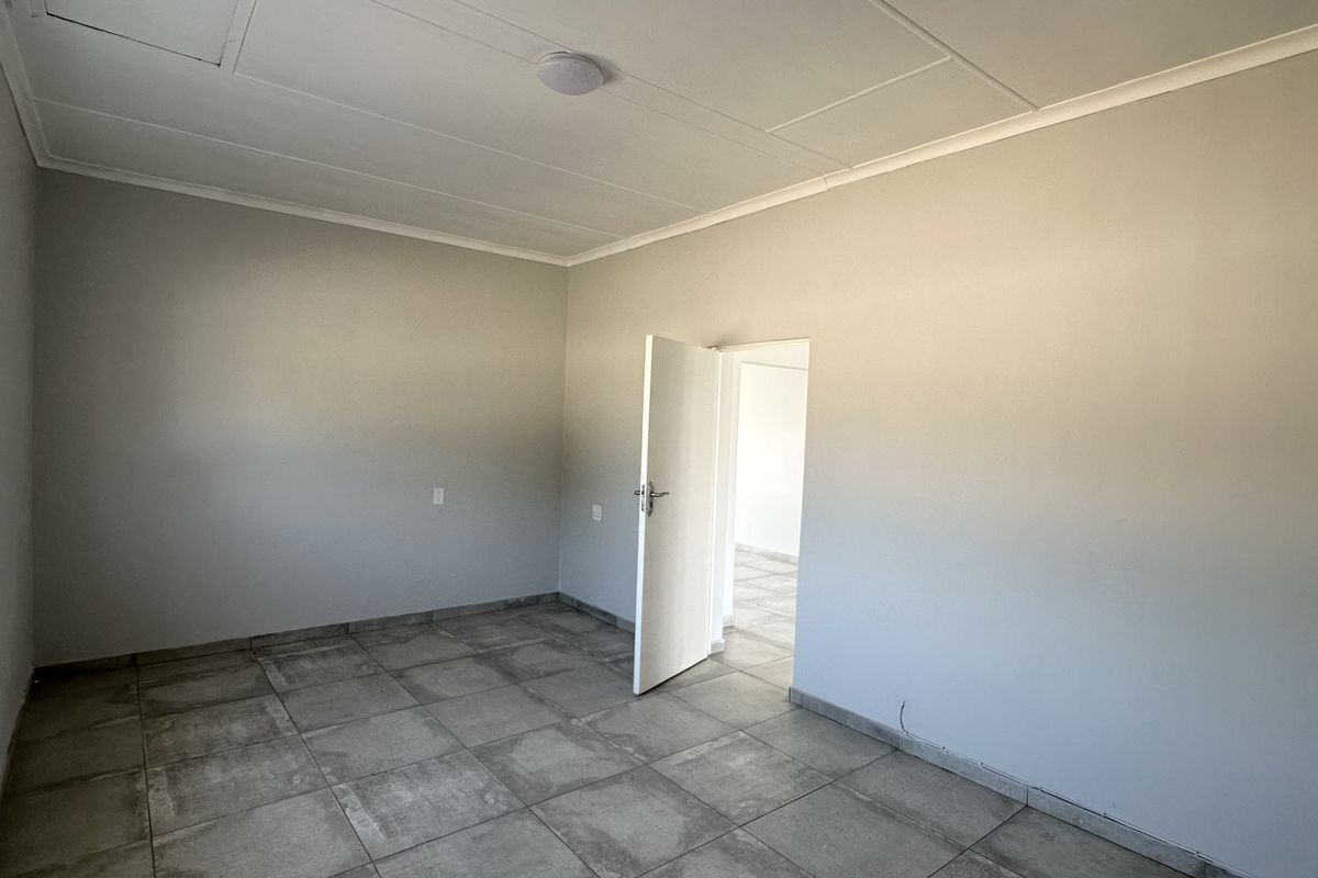 A clean, empty bedroom featuring neutral grey tiled flooring and a simple ceiling finish, offering a blank canvas for personalization.