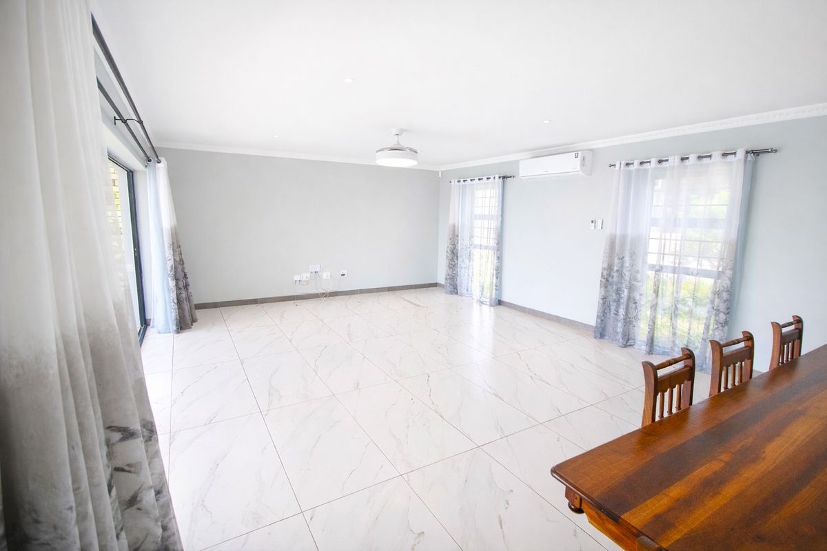 Spacious, light-filled living area featuring modern marble-look floor tiles, split-system air conditioning, and large sliding glass doors leading to the exterior.