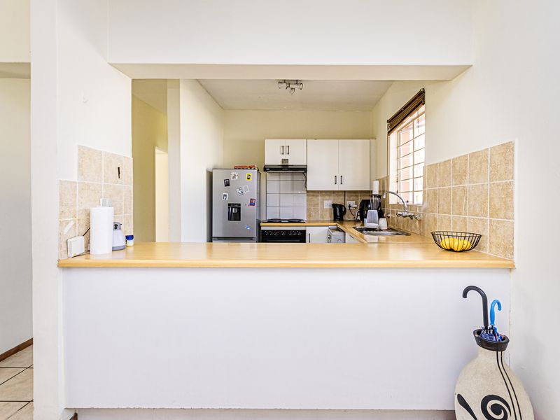 A functional kitchen featuring built-in cabinetry, a laminate breakfast bar, tiled backsplash, and integrated cooking appliances, offering a practical layout for daily use.