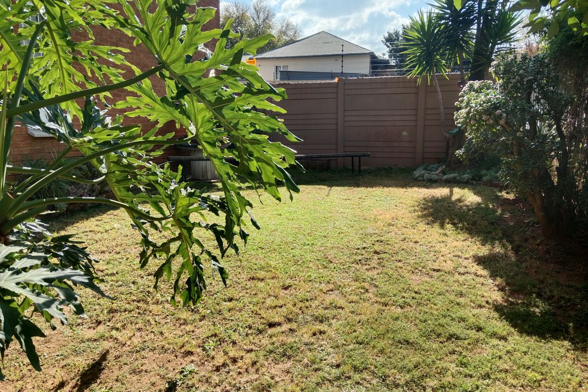 A private rear garden featuring a lawn area enclosed by a solid boundary wall, offering a quiet outdoor space for the townhouse.